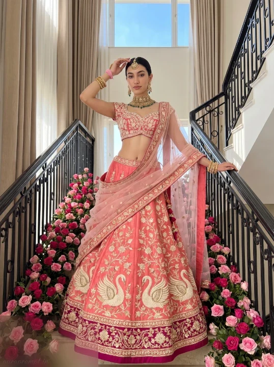 Girl in coral swan lehenga with sheer pink dupatta standing on flower-lined staircase, full-length AI lehenga photo prompt portrait